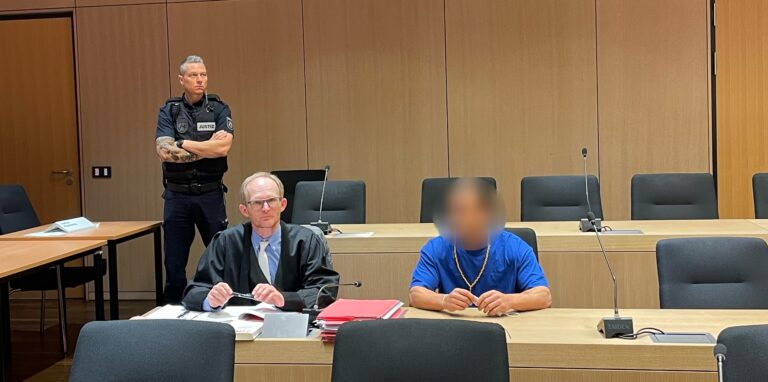 Ein Justizmitarbeiter, ein Verteidiger und ein unkenntlich gemachter Angeklagter sitzen in einem Gerichtssaal in Recklinghausen.
