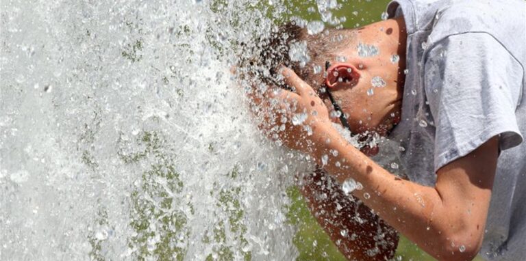 Bei Temperaturen um 29 Grad Celsius erfrischt sich ein junger Mann im Berliner Lustgarten am Wasser eines Brunnens.