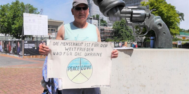 Detlef Kihm steht mit einem Schild in der Hand auf dem Creiler Platz in Marl.