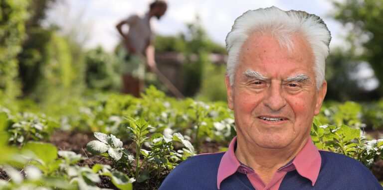 Montage: Nahaufnahme eines Gemüsebeets, in dem im Hintergrund unscharf ein Mann harkt, dazu das Foto eines älteren Mannes.
