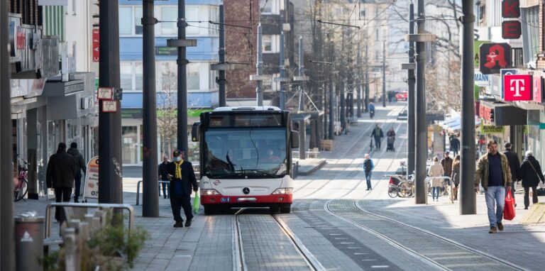 Ein Linienbus fährt durch eine Innenstadt.