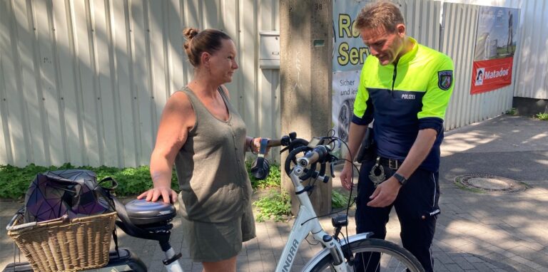 Eine Frau und ein Polizist stehen an einem Fahrrad auf der Castroper Straße in Recklinghausen