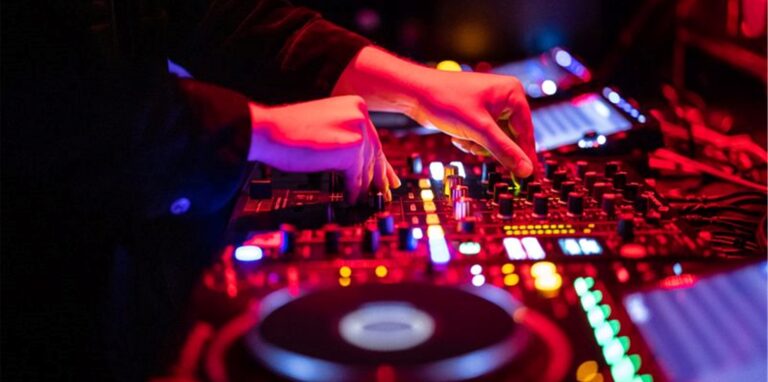Ein DJ steht in einem Club am Mischpult.
