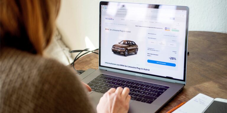 Eine Frau sitzt an einem Computer und betrachtet ein Angebot eines Auto-Händlers.
