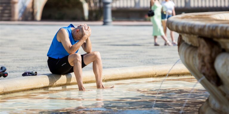 Ein Mann kühlt sich im zentralen Brunnen auf der Plaza de España in Sevilla ab