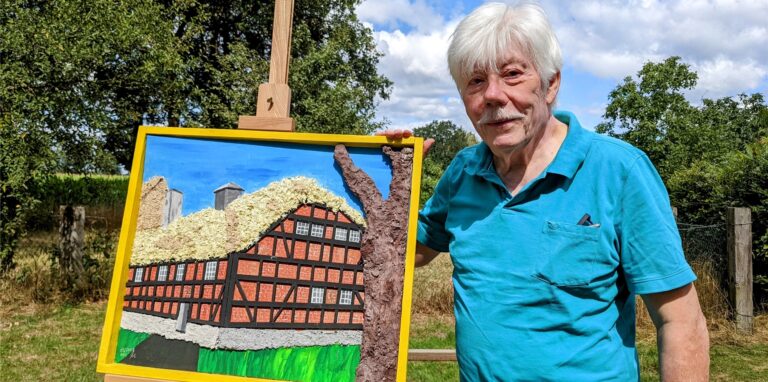 Karl-Heinz Lucks mit einem Gemälde seines 3D-Fachwerkhauses.