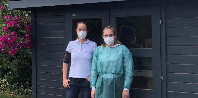 Dr. Mareike Klemm und Mitarbeiterin Lena Mateblowski (von links) stehen vor dem Testzentrum hinter der Arztpraxis Dr. Voigt und Finke an der Hardtstraße 8 in Dorsten-Östrich. In dem kleinen Gartenhaus bieten sie weiterhin Corona-Tests an und übernehmen dabei für ihre Kundinnen und Kunden die Selbstbeteiligung von drei Euro.