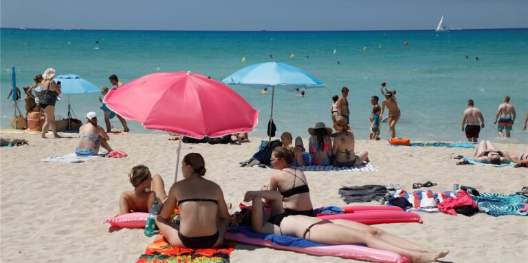 Menschen schwimmen und sonnen sich am Strand von Arenal auf Mallorca.