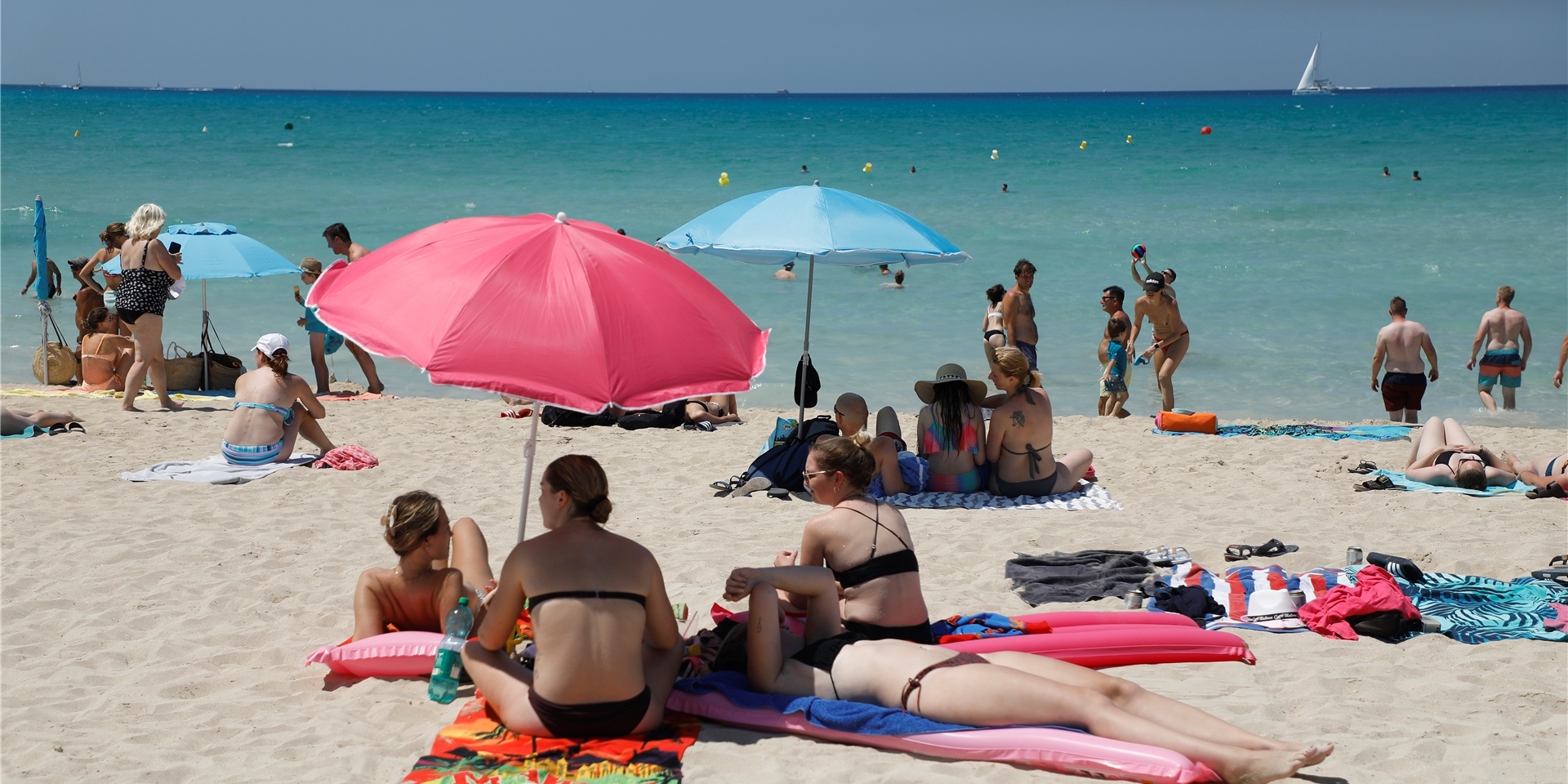 Menschen schwimmen und sonnen sich am Strand von Arenal auf Mallorca.