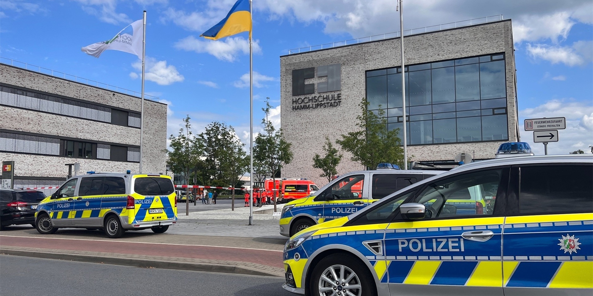 An der Hochschule Hamm-Lippstadt hat ein 34-jähriger Mann mit einem Messer mehrere Menschen angegriffen und vier Personen verletzt, einige von ihnen schwer. Polizeiwagen stehen auf dem Campus.