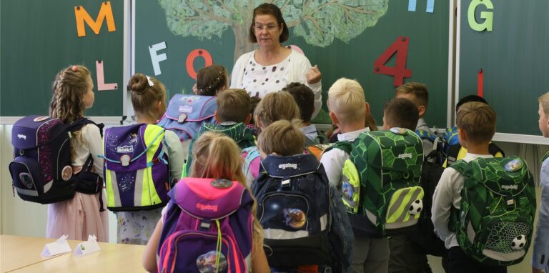 Eine Lehrerin steht vor Schülern der ersten Klasse.