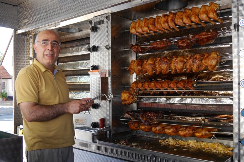 Rezger Dohouki verkauft Hähnchen und Haxen vom Drehspieß.