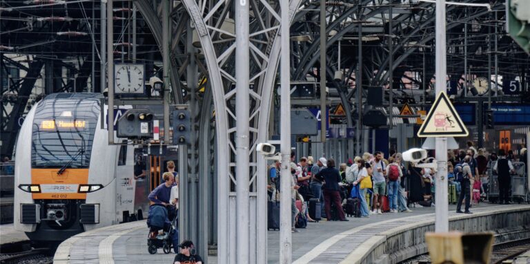 Reisende warten auf einem Bahnsteig im Hauptbahnhof auf ihren Zug.