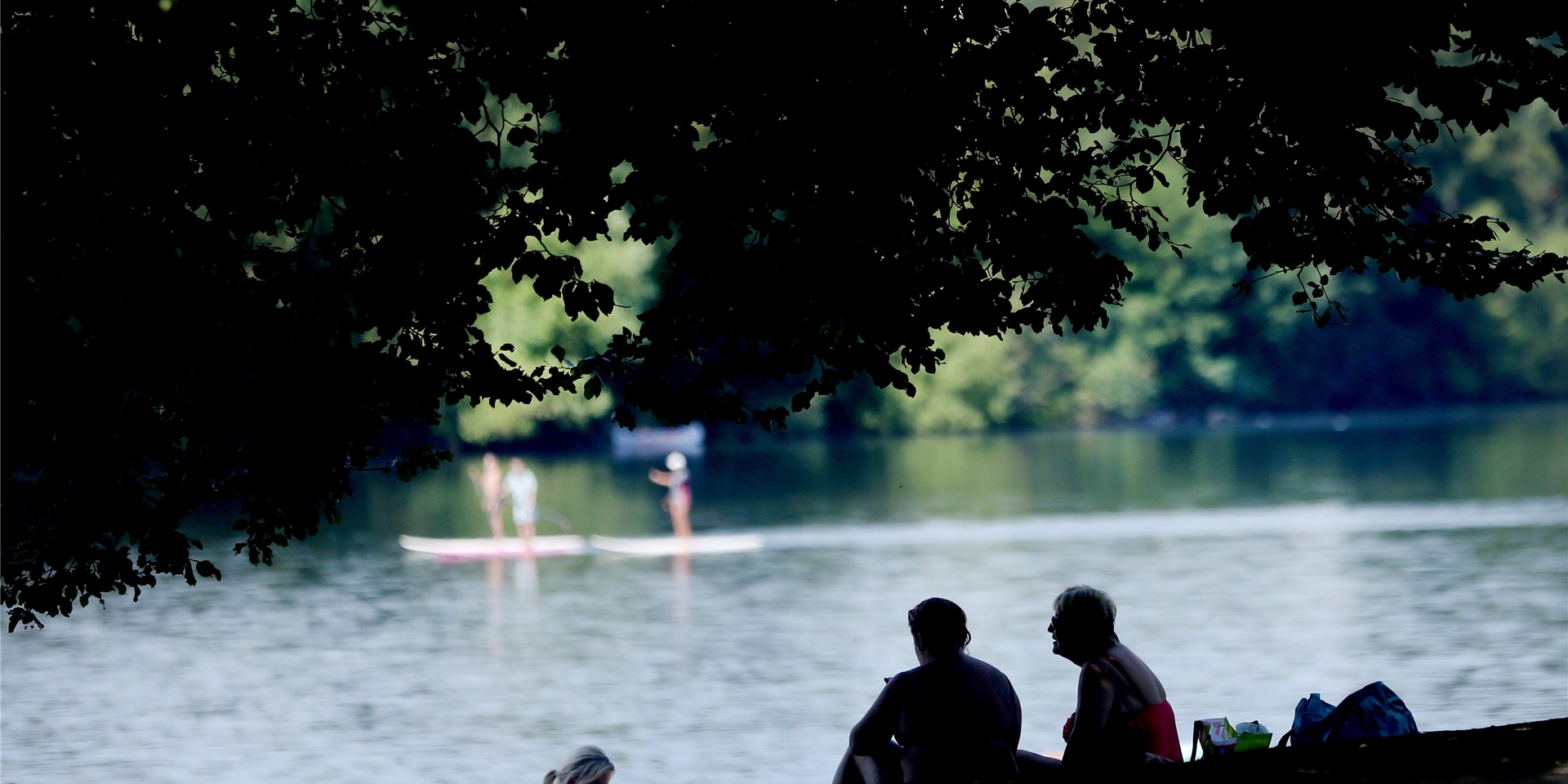 Im kühlen Schatten eines großen Baumes verbringen zwei Frauen ihre Freizeit am Masurensee der Sechs-Seen-Platte.