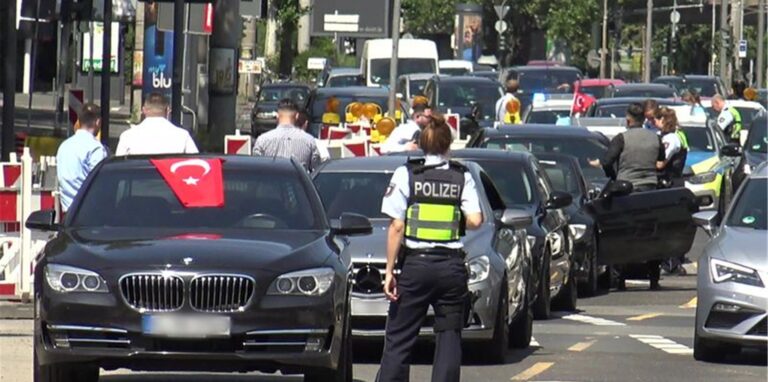 Eine Polizistin der Polizei NRW steht vor den Fahrzeugen eines angehaltenen türkischen Hochzeitskorsos.