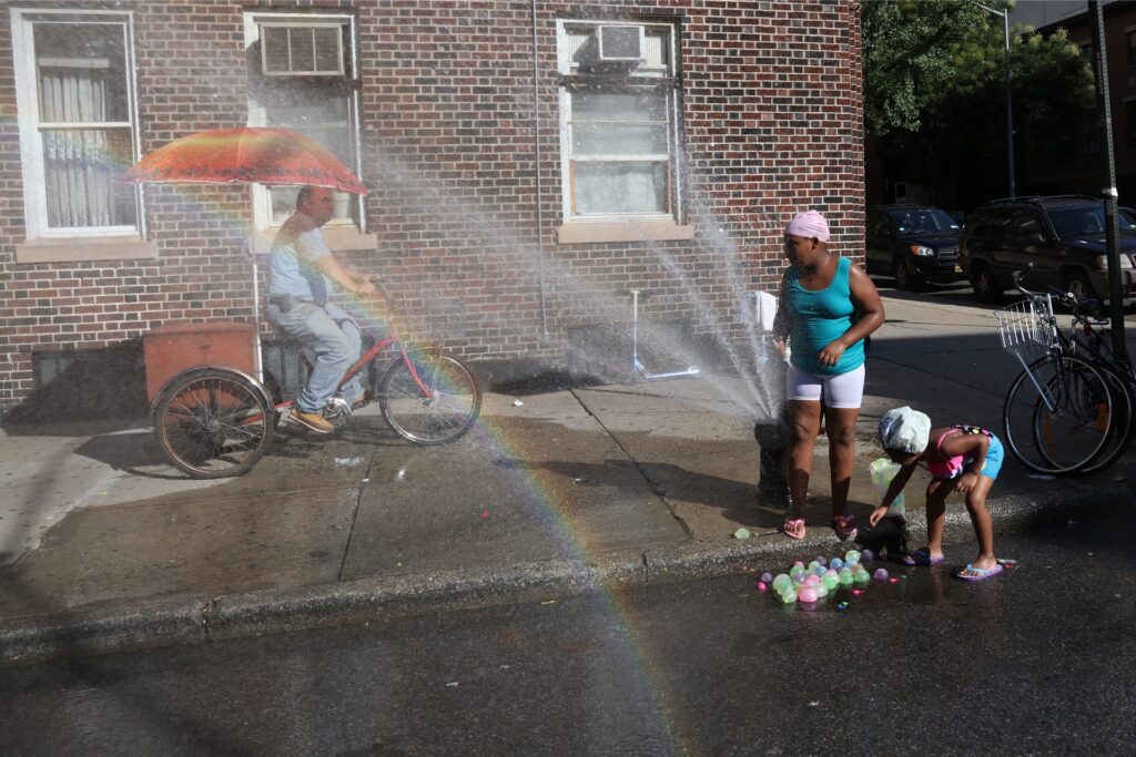 Kinder spielen in einem offenen Hydranten im Stadtteil Williamsburg bei Temperaturen über 32 Grad. Kinder spielen in einem offenen Hydranten im Stadtteil Williamsburg bei Temperaturen über 32 Grad.