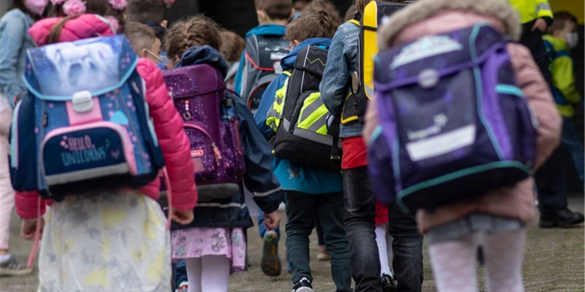 Kinder laufen in ihr Klassenzimmer mit ihren Schultaschen.
