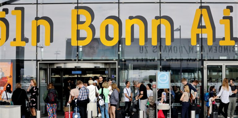 Reisende stehen vor dem Eingang zum Köln-Bonner Flughafen.