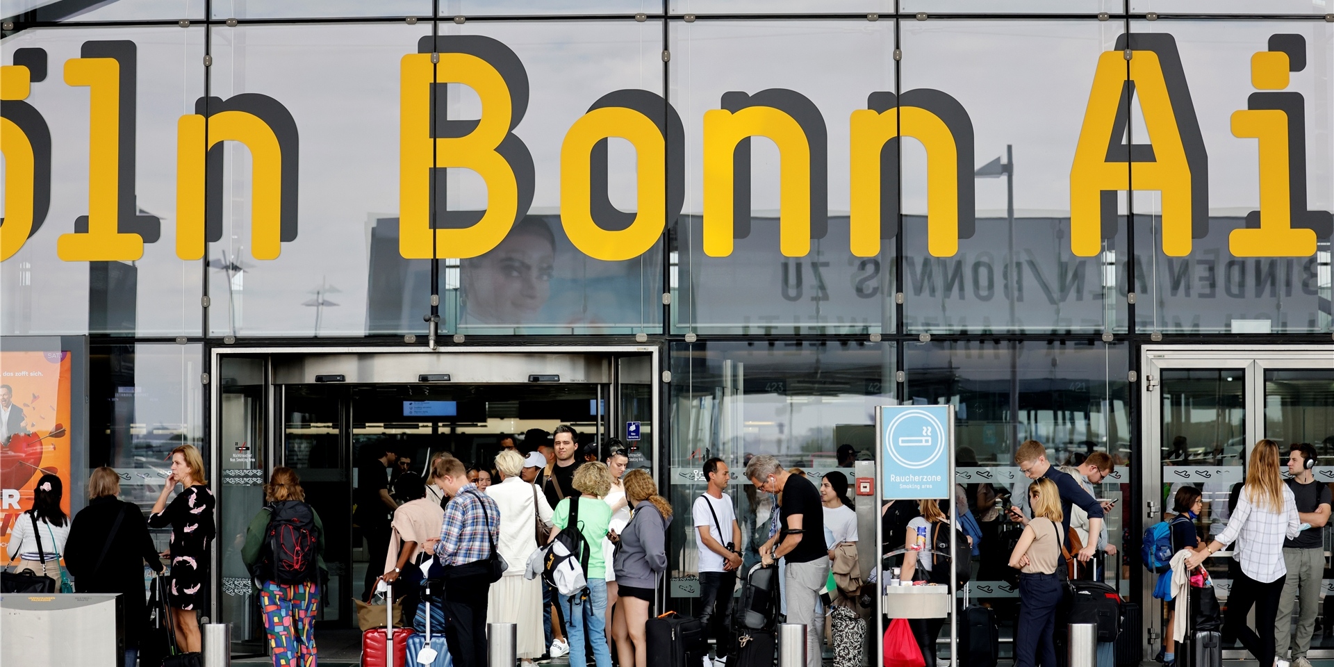 Reisende stehen vor dem Eingang zum Köln-Bonner Flughafen.
