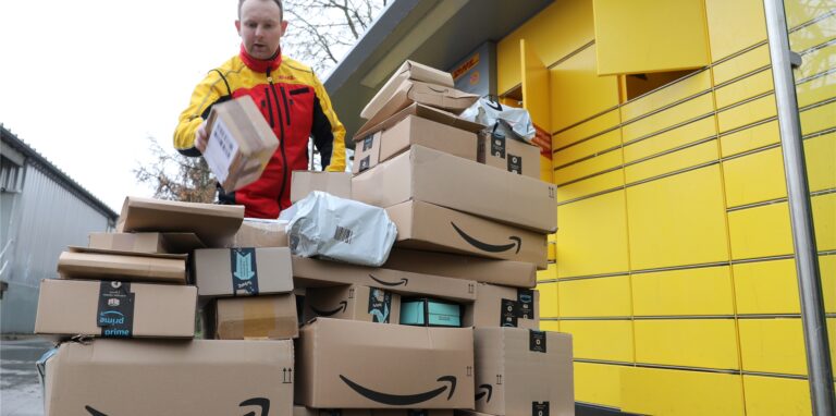 Ein Paketbote vor einer Packstation der DHL.