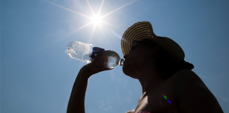 Eine Frau mit Sonnenhut trinkt am 03.07.2015 in Recklinghausen (Nordrhein-Westfalen) unter der Mittagssonne aus einer Wasserflasche