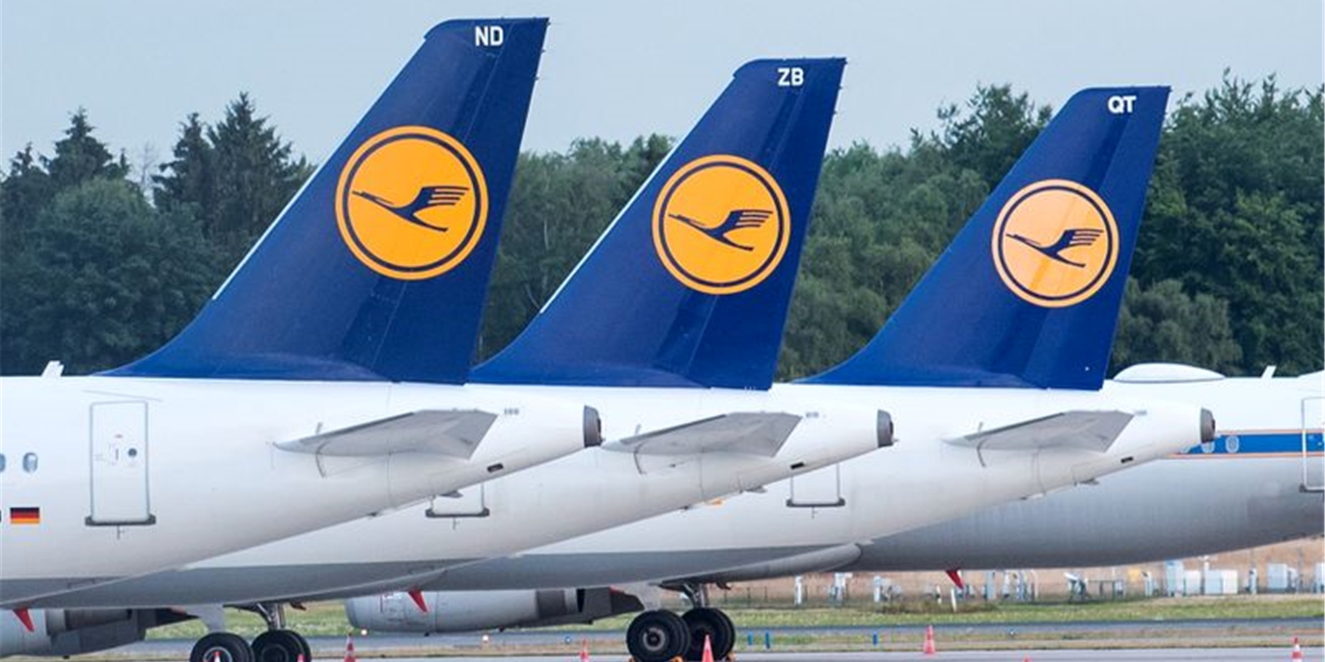 Flugzeuge der Lufthansa stehen auf dem Gelände eines Flughafens.