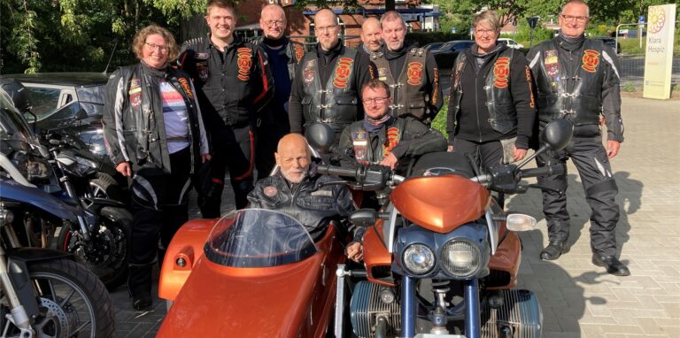 Eingerahmt von den Motorradfahrerinnen und -fahrern des Clubs Red Knights Dorsten sitzt Klaus Vogtländer im Beiwagen. Links steht Pflegefachkraft und Bikerin Elke Siepmann, die die geniale Idee für diesen Ausflug hatte.