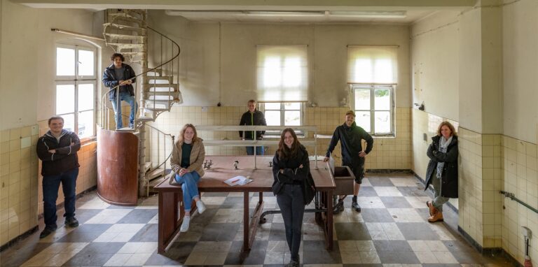 Die Studierenden (v.l.) Timo Stickan, Amr Abouawad, Julia Rott, Mats Potthast, Nina Kock, Kevin Lehmann mit ihrer Dozentin Elfriede Heidhoff in einem Laborgebäude.