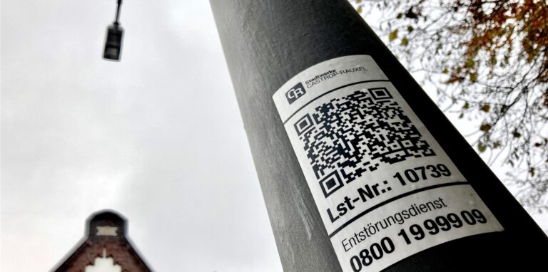 An der Holzstraße ist die Straßenbeleuchtung gerade auf LED umgerüstet worden. Über die QR-Codes kann man Störungen per Handy direkt melden. Das geht aber nach wie vor auch telefonisch.