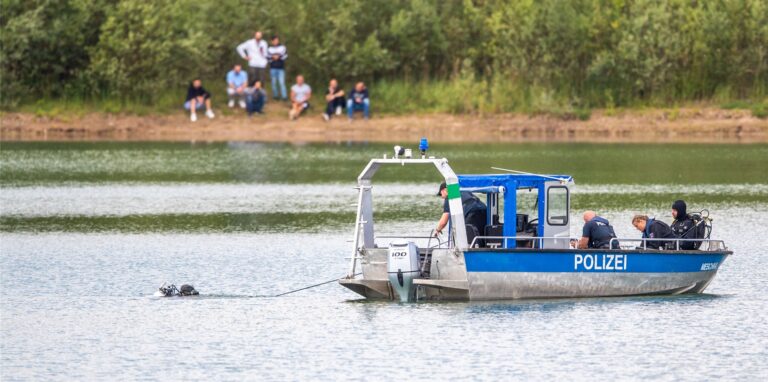 Ein Polizeiboot mit Tauchern der Taucheinheit Bochum ist auf einem Kiesteich im Einsatz.