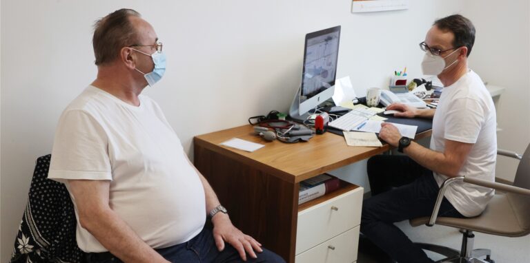 Ein Hausarzt im Gespräch mit einem Patienten.