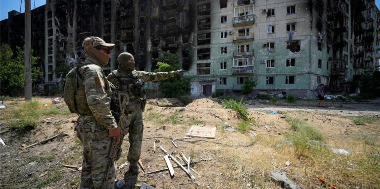 Russische Soldaten unterhalten sich in der Nähe eines Wohnhauses.