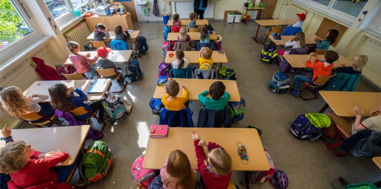 Schüler einer ersten Grundschulklasse sitzen im Unterricht auf ihren Plätzen.