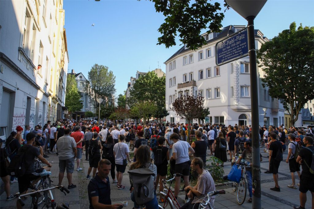 Am Dienstagabend (9.8.) haben sich rund 200 Teilnehmende auf dem Kurt-Phiel-Platz in der Dortmunder Nordstadt versammelt. Anlass war der tödliche Polizeieinsatz auf dem Gelände der St. Antonius Gemeinde, bei dem ein 16-Jähriger von einem Polizisten erschossen worden ist. Am Dienstagabend (9.8.) haben sich rund 200 Teilnehmende auf dem Kurt-Phiel-Platz in der Dortmunder Nordstadt versammelt. Anlass war der tödliche Polizeieinsatz auf dem Gelände der St. Antonius Gemeinde, bei dem ein 16-Jähriger von einem Polizisten erschossen worden ist.