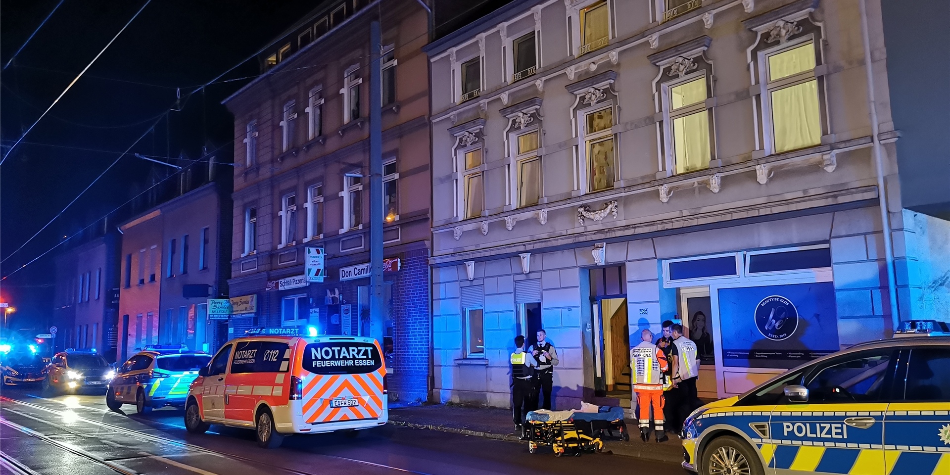 Streifenwagen, ein Notarztwagen sowie Sanitäter und Polizeibeamte stehen an der Steeler Straße in Essen vor der Wohnung, in der ein 15-Jähriger seinen 19-Jährigen Bruder getötet haben soll.