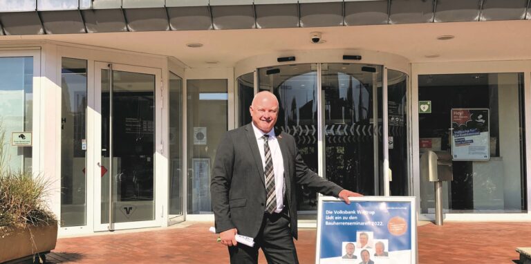 Michael Scholten, Niederlassungsleiter der Waltroper Volksbank, steht neben einem Plakat vor dem Haupteingang.