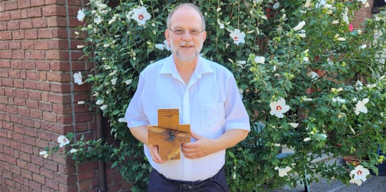 Pfarrer Michael Sturm aus Recklinghausen hält ein Holzkreuz in den Händen