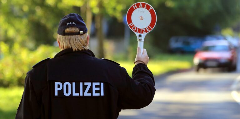 Ein Polizist winkt während einer Geschwindigkeitskontrolle ein Auto an den Fahrbahnrand.