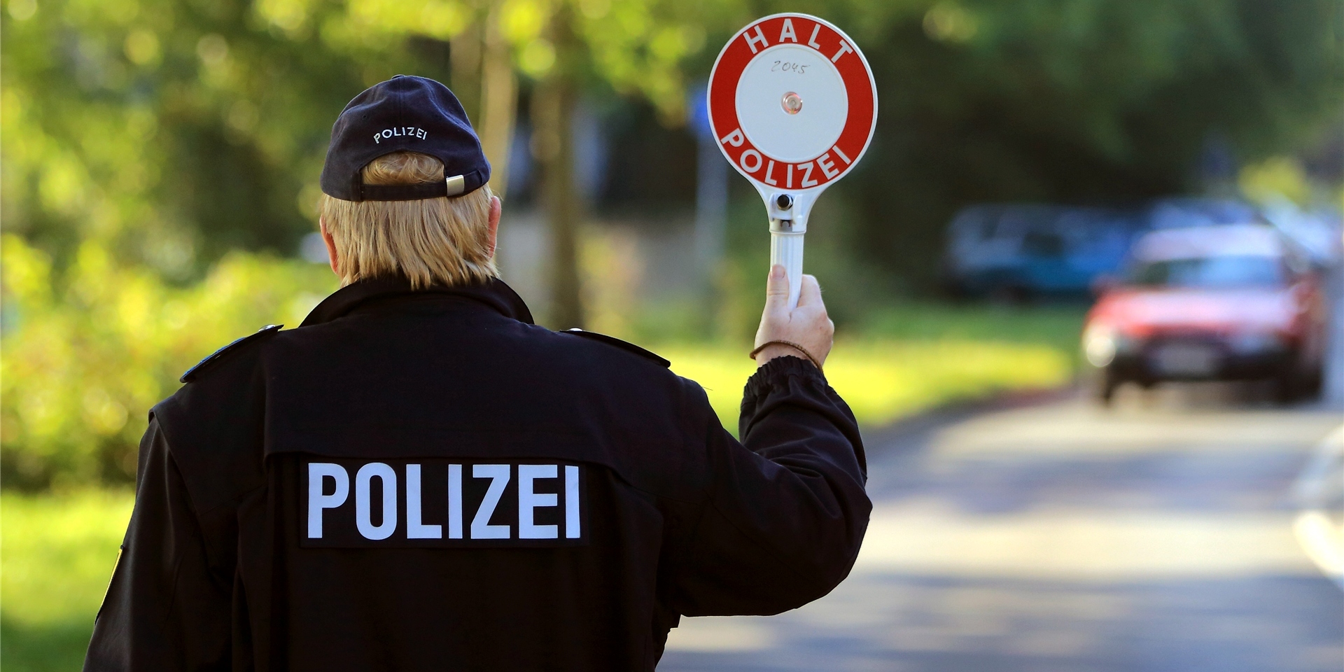 Ein Polizist winkt während einer Geschwindigkeitskontrolle ein Auto an den Fahrbahnrand.