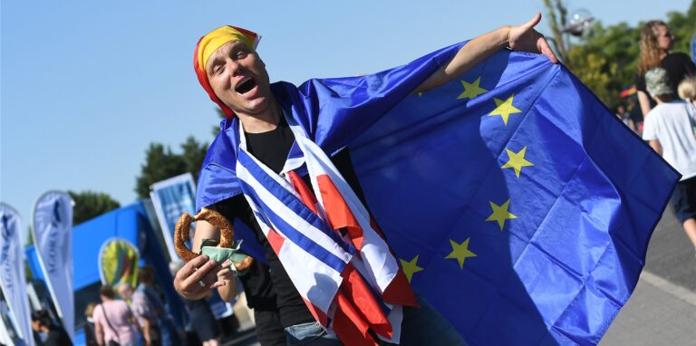 Ein Besucher des Europafests 2022 in Castrop-Rauxel trägt die Europafahne um seine Schultern, die Deutschlandfahne um den Kopf gewickelt und die Fahnen der Partnerstädte Castrop-Rauxels als Schal.
