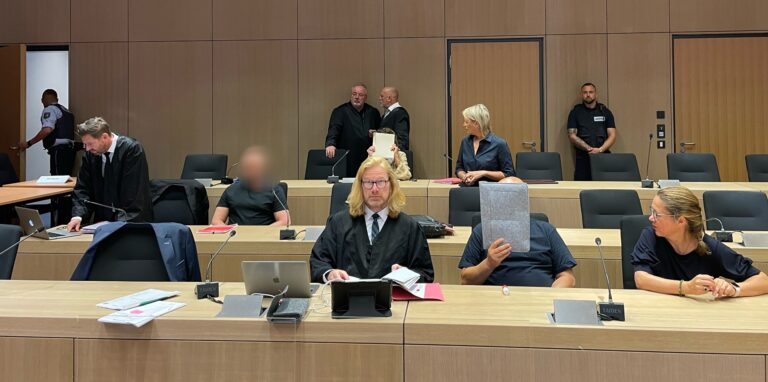 Die Angeklagten im „Ostring-Prozess“ kurz vor Prozessbeginn im Gerichtssaal: Die Vermieterin aus Herten sitzt in der hinteren Reihe mittig (Gesicht mit Aktendeckel verdeckt). In der 2. Reihe sitzt der geständige Niederländer, vorne in der Mitte der mutmaßliche Chemikalien-Besorger.
