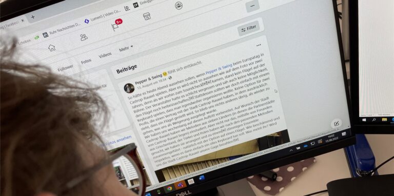 Auf einem Schreibtisch steht ein Bildschirm, der die Facebook-Seite des Jazzduos Pepper & Swing zeigt.