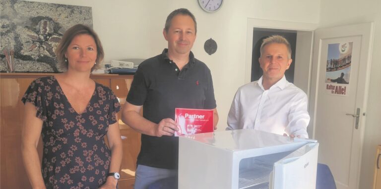 Christian Eichten – hier mit zwei Caritas-Mitarbeitern – spendet einen Kühlschrank für einen Wohnungslosen.