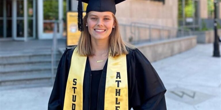 Eine junge Frau steht im typischen Studien-Abschluss-Outfit vor der Uni in Richmond/USA.