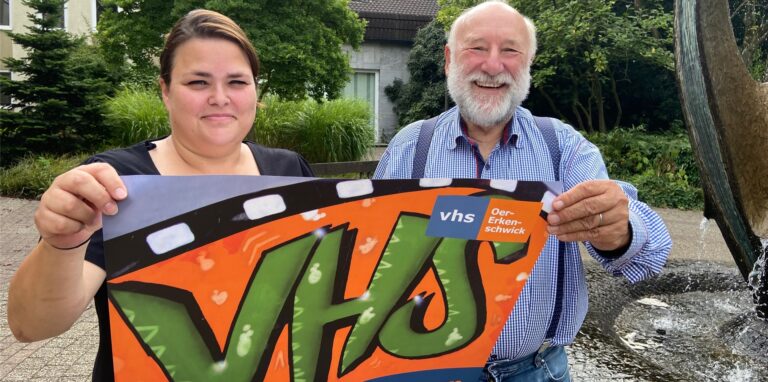 Diana Schweden und Ralf Rieder mit einem Plakat der VHS Oer-Erkenschwick vor dem Rathaus