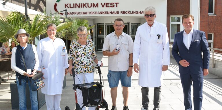 Drei ehemalige Patienten stehen mit drei Medizinern vor dem Knappschaftskrankenhaus Klinikum Vest in Recklinghausen.