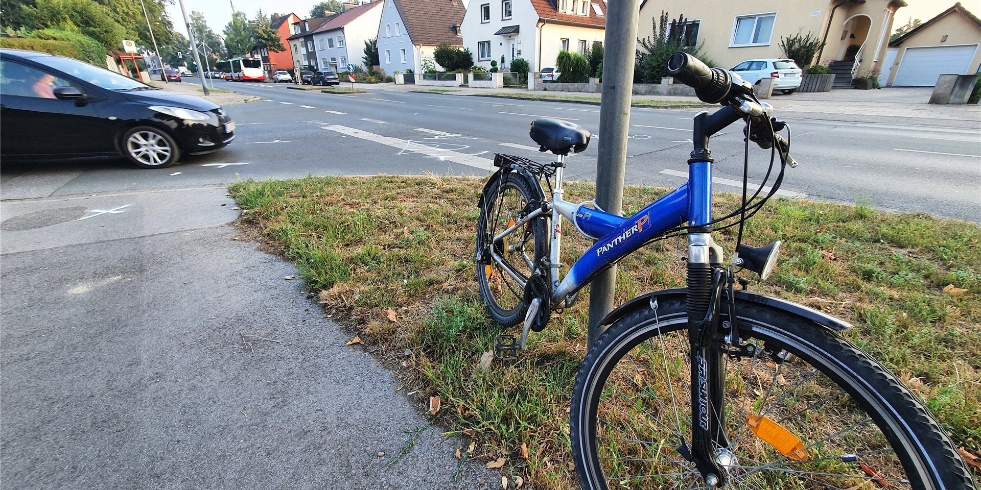 Nach dem Unfall an der Ecke Feldstraße/Buschstraße ist das Mountainbike des verletzten 29-jährigen an einem Verkehrsschild befestigt worden. Auf der Fahrbahn sind Markierungen der Polizei zu erkennen.