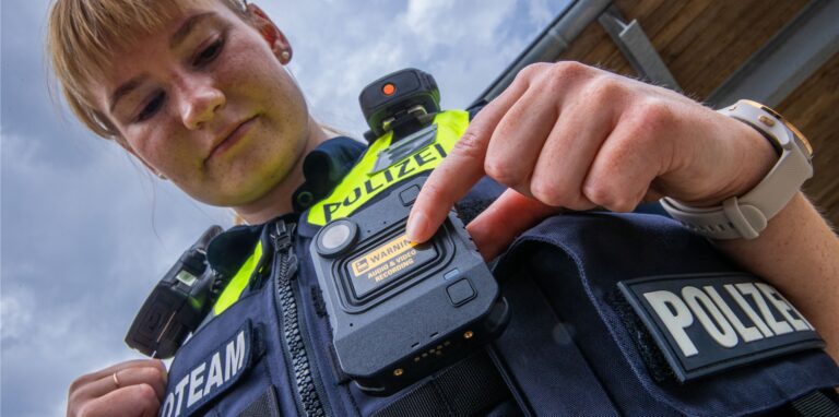 Eine Polizistin zeigt ihre Bodycam.