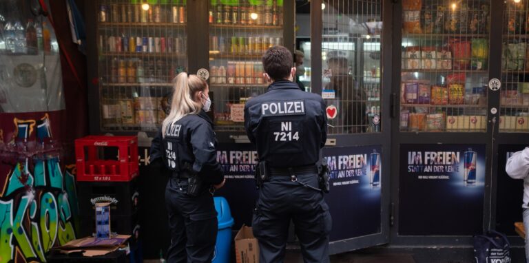 Polizisten stehen bei einer Kontrolle an einem Kiosk.