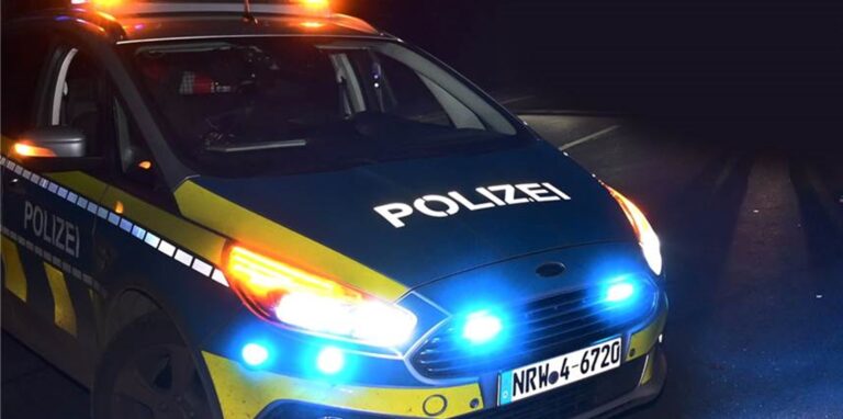 Ein Auto der Polizei NRW steht spät in der Nacht auf einer Straße.